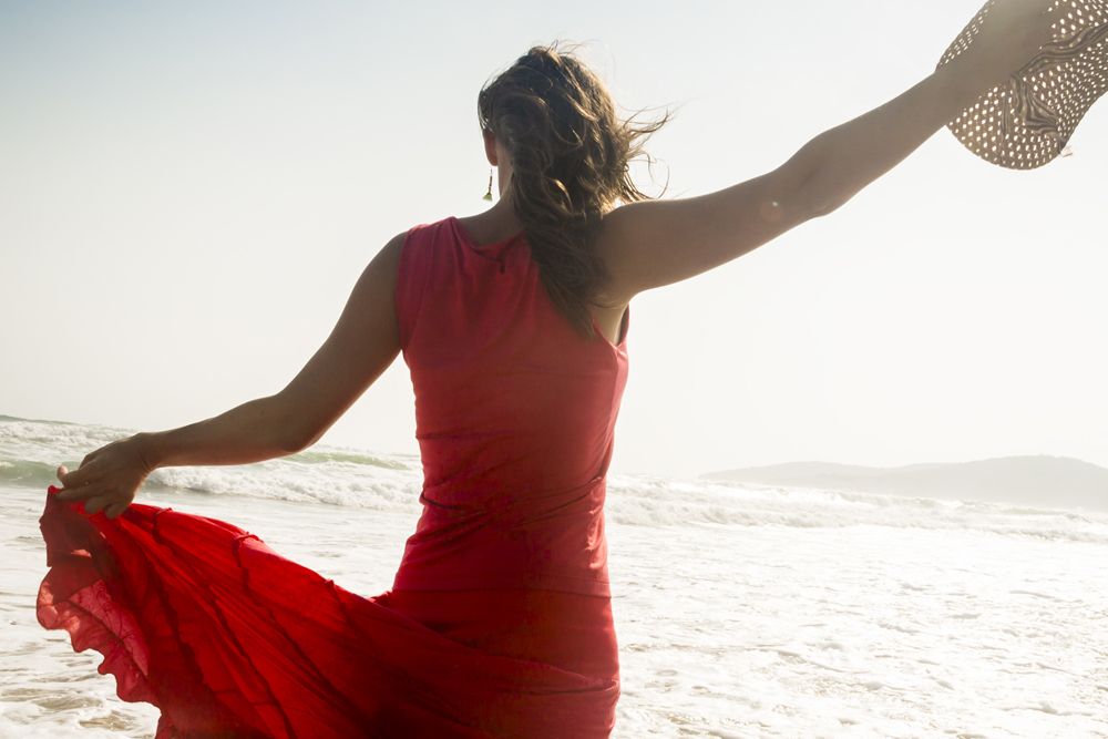 Woman on beach raising arms