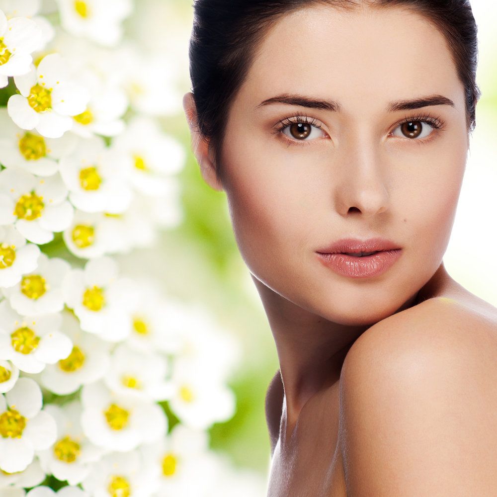 A beautiful woman standing next to white flowers.