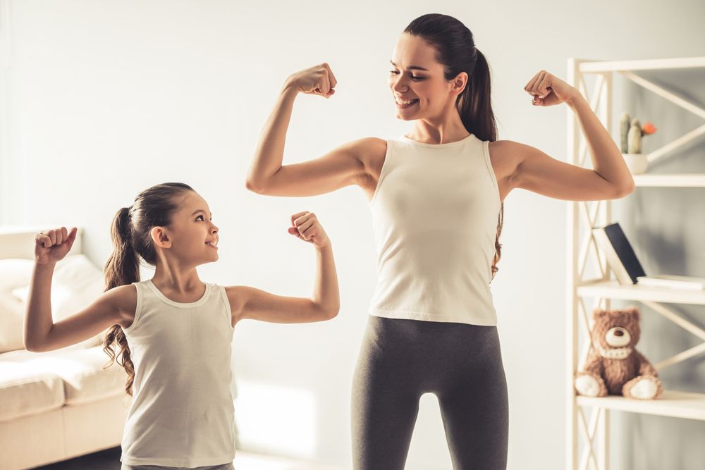 Mother and daughter flexing biceps together